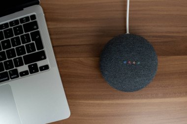 Google Home Mini kömür akıllı hoparlör ahşap bir masa üzerinde.