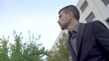 Modern iş adamı, kendine güveni tam yakışıklı iş adamı ofis binasına karşı siyah takım elbiseli, açık hava işçi portresi.