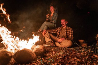 Ormanda sıcak ve sıcak bir kamp ateşinde genç bir çift. Güzel bayan ve yakışıklı çocuk kamp yaparken ateşin etrafında birbirlerine aşıklar..