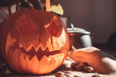 Masada mum ve güneş ışığı olan Cadılar Bayramı hayaleti kabak suratlı. İskelet, mum, fındık. Teal ve turuncu güzel natürmort.