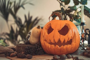 Masada mum ve güneş ışığı olan Cadılar Bayramı hayaleti kabak suratlı. İskelet, mum, fındık. Teal ve turuncu güzel natürmort.