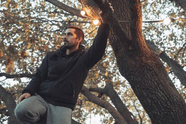 Yakışıklı genç adam sonbahar güneşli sabahında sisli ormanda tek başına yürüyor. Sıcak vintage renkler.