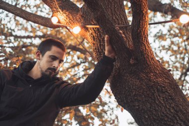 Yakışıklı genç adam sonbahar güneşli sabahında sisli ormanda tek başına yürüyor. Sıcak vintage renkler.