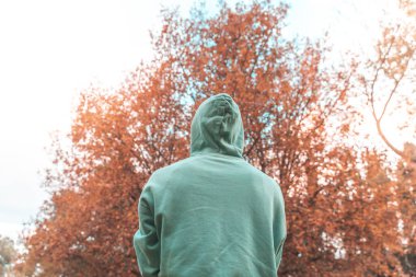 Coronavirus. Koronavirüs yüzünden karantinada olan bir adam sonbaharda koruyucu maske takıyor ve kaput takıyor. Evde kal..