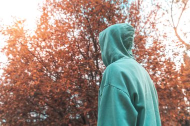 Coronavirus. Koronavirüs yüzünden karantinada olan bir adam sonbaharda koruyucu maske takıyor ve kaput takıyor. Evde kal..