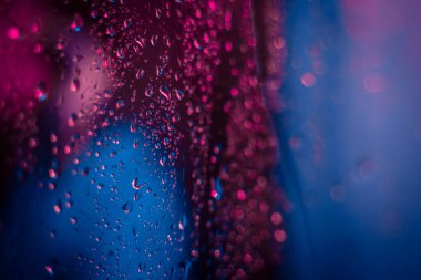 Dramatik neon ışıklı pencere, yağmur damlalarıyla. Parlak renkli. Korkunç ve korkunç bir kavram..