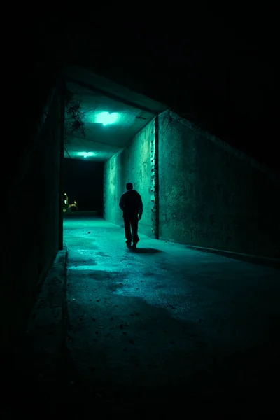 Lonely man in a dark alley at night. Danger and scary concept.
