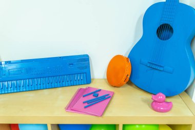 Ahşap bir rafta renkli nesneler, oyuncaklar ve enstrümanlar. Parti renkli nesneleri ve balonları.