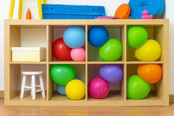 Pop colorful objects, toys and instruments on a wooden shelf. Party vivid color objects and balloons.