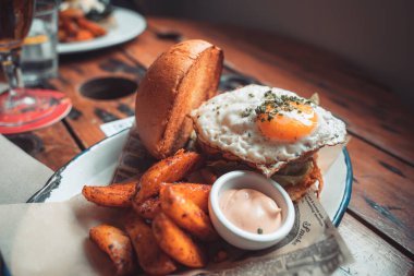 Susamlı ekmeğin içinde bütün gün kahvaltılık burger, kızarmış yumurta ve pastırma. Hippi yemeği. Metin için kopyalama alanı olan yiyecek pornosu.