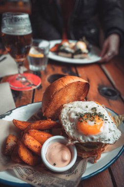 Susamlı ekmeğin içinde bütün gün kahvaltılık burger, kızarmış yumurta ve pastırma. Hippi yemeği. Metin için kopyalama alanı olan yiyecek pornosu.