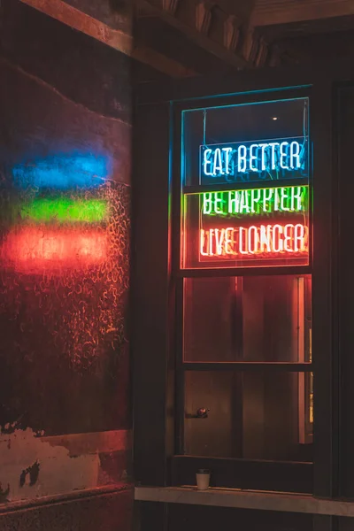 Neon sign, bright glowing advertising. Eat better, be happier, live longer.