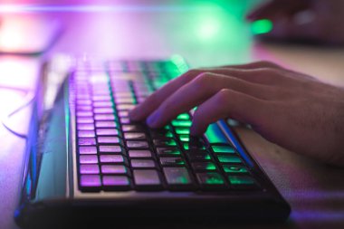 Kişisel bilgisayarında video oyunu oynayan profesyonel bir oyuncunun klavyesine yakın çekim elleri. Retro Arcade Style.Cyber Şampiyonası 'nda Neon Lights' ın aydınlattığı oda. Görüntü Bokeh 'e dönüşür.