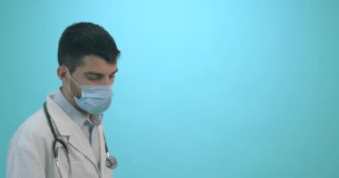 Tıbbi maskeli bir erkek doktor mavi arka planda Corona virüsü aşısı olan bir şırınga tutuyor. Grip, kızamık, koronavirüs aşısı aşısı aşısı. Coronavirus aşısı. 