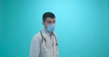 Tıbbi maskeli bir erkek doktor mavi arka planda Corona virüsü aşısı olan bir şırınga tutuyor. Grip, kızamık, koronavirüs aşısı aşısı aşısı. Coronavirus aşısı.