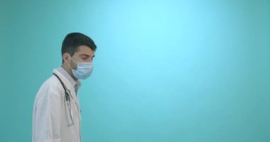 Tıbbi maskeli bir erkek doktor mavi arka planda Corona virüsü aşısı olan bir şırınga tutuyor. Grip, kızamık, koronavirüs aşısı aşısı aşısı. Coronavirus aşısı.