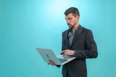 Dizüstü bilgisayarıyla çalışan bir iş adamı mavi arka planda izole edilmiş. Teknoloji ve finans kavramı. Metin için Boş Alan
