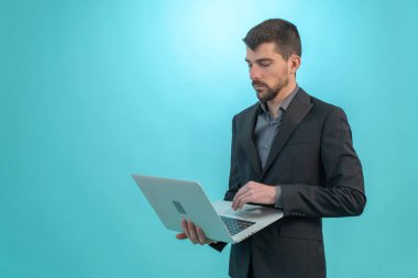 Dizüstü bilgisayarıyla çalışan bir iş adamı mavi arka planda izole edilmiş. Teknoloji ve finans kavramı. Metin için Boş Alan