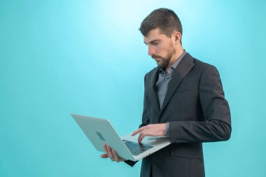 Dizüstü bilgisayarıyla çalışan bir iş adamı mavi arka planda izole edilmiş. Teknoloji ve finans kavramı. Metin için Boş Alan