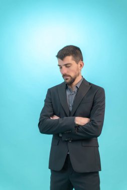 Genç iş adamı mavi arka planda soyutlanmış olarak yere bakıyor. Teknoloji konsepti. Metin için Boş Alan