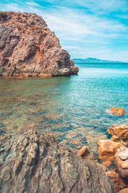 Güzel kayalık kıyı manzarası ve harika kristal mavi okyanus. Akdeniz 'in sarp kayalıklı turkuaz suyu.