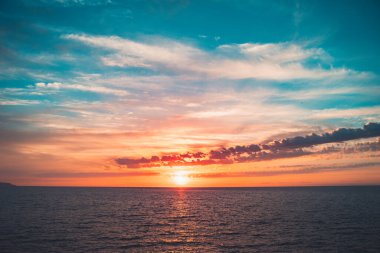 Denizde parlak, güzel bir gün doğumu. Sakin bir okyanusa yansıyan güneşin manzarası