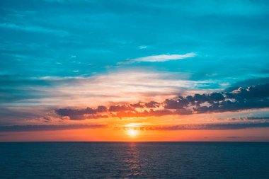 Denizde parlak, güzel bir gün doğumu. Sakin bir okyanusa yansıyan güneşin manzarası