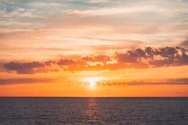 Denizde parlak, güzel bir gün doğumu. Sakin bir okyanusa yansıyan güneşin manzarası