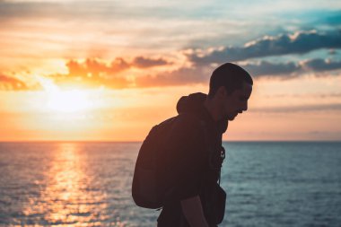 İnsan silueti uçurumun kenarında yürür ve güzel renkli gökyüzü ile denize bakar. Özgürlüğün tadını çıkarıyorum.