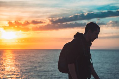 İnsan silueti uçurumun kenarında yürür ve güzel renkli gökyüzü ile denize bakar. Özgürlüğün tadını çıkarıyorum.
