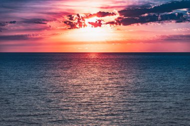 Denizde parlak, güzel bir gün doğumu. Sakin bir okyanusa yansıyan güneşin manzarası