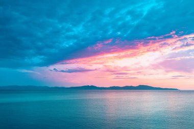 Denizde parlak, güzel bir gün doğumu. Okyanusun üzerindeki renkli bir gökyüzünün manzarası. Pembe ve mavi bulutlar.