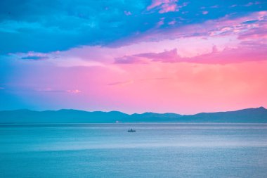 Denizde parlak, güzel bir gün doğumu. Okyanusun üzerindeki renkli bir gökyüzünün manzarası. Pembe ve mavi bulutlar.