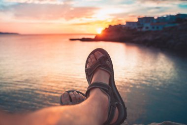 Çıplak ayaklı genç bir adamın bakış açısı deniz sahilinde gün batımında inanılmaz görünür. Akdeniz yaz tatillerinde dinlenir.