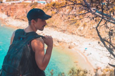 Akdeniz kıyı şeridi manzaralı destansı ve ilham verici genç gezgin dağ kayalıklarından türkuaz suya bakıyor. Katalonya sahilinde yaz tatili. İspanya kıyı şeridinde sırt çantaları.