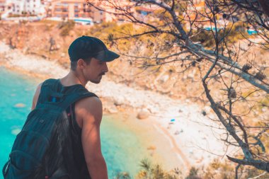 Akdeniz kıyı şeridi manzaralı destansı ve ilham verici genç gezgin dağ kayalıklarından türkuaz suya bakıyor. Katalonya sahilinde yaz tatili. İspanya kıyı şeridinde sırt çantaları.