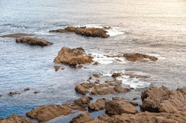 Gün batımında dalgaların inanılmaz gücü kayalara çarpıyor. Büyük okyanus dalgası kıyıları kırıyor. Doğa kavramının güzelliği. Güzel deniz manzarası. Duvar kağıdı, arkaplan.
