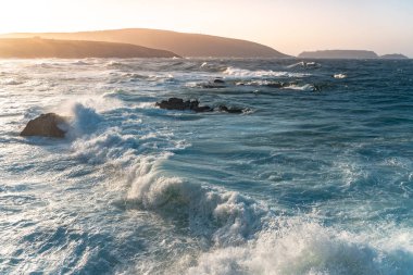 Gün batımında dalgaların inanılmaz gücü kayalara çarpıyor. Büyük okyanus dalgası kıyıları kırıyor. Doğa kavramının güzelliği. Güzel deniz manzarası. Duvar kağıdı, arkaplan.