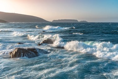 Gün batımında dalgaların inanılmaz gücü kayalara çarpıyor. Büyük okyanus dalgası kıyıları kırıyor. Doğa kavramının güzelliği. Güzel deniz manzarası. Duvar kağıdı, arkaplan.