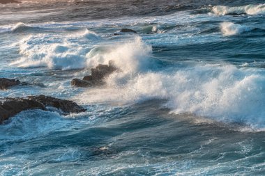 Gün batımında dalgaların inanılmaz gücü kayalara çarpıyor. Büyük okyanus dalgası kıyıları kırıyor. Doğa kavramının güzelliği. Güzel deniz manzarası. Duvar kağıdı, arkaplan.