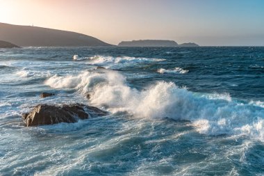 Gün batımında dalgaların inanılmaz gücü kayalara çarpıyor. Büyük okyanus dalgası kıyıları kırıyor. Doğa kavramının güzelliği. Güzel deniz manzarası. Duvar kağıdı, arkaplan.