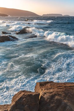 Gün batımında dalgaların inanılmaz gücü kayalara çarpıyor. Büyük okyanus dalgası kıyıları kırıyor. Doğa kavramının güzelliği. Güzel deniz manzarası. Duvar kağıdı, arkaplan.