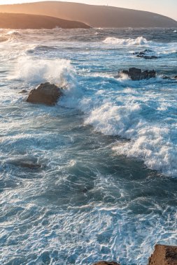 Gün batımında dalgaların inanılmaz gücü kayalara çarpıyor. Büyük okyanus dalgası kıyıları kırıyor. Doğa kavramının güzelliği. Güzel deniz manzarası. Duvar kağıdı, arkaplan.