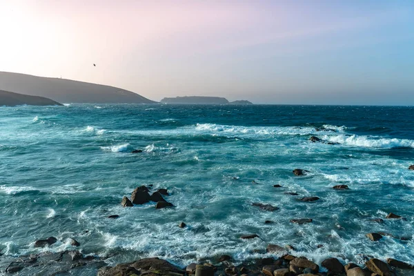Gün batımında dalgaların inanılmaz gücü kayalara çarpıyor. Büyük okyanus dalgası kıyıları kırıyor. Doğa kavramının güzelliği. Güzel deniz manzarası. Duvar kağıdı, arkaplan.