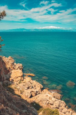 Güzel kayalık kıyı manzarası ve harika kristal mavi okyanus. Akdeniz 'in sarp kayalıklı turkuaz suyu. Seyahat ve tatil konsepti. Arkaplan ve duvar kağıdı.
