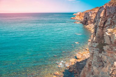 Güzel kayalık kıyı manzarası ve harika kristal mavi okyanus. Akdeniz 'in sarp kayalıklı turkuaz suyu. Seyahat ve tatil konsepti. Arkaplan ve duvar kağıdı.