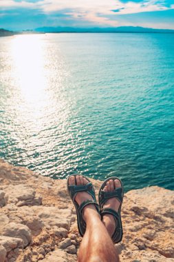 Parmak arası terlikleri olan genç bir adamın kumsalda gün batımına bakışı inanılmaz. Akdeniz yaz tatillerinde dinlenir. Tatil kavramı.