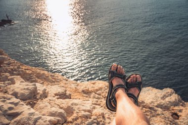 Parmak arası terlikleri olan genç bir adamın kumsalda gün batımına bakışı inanılmaz. Akdeniz yaz tatillerinde dinlenir. Tatil kavramı.