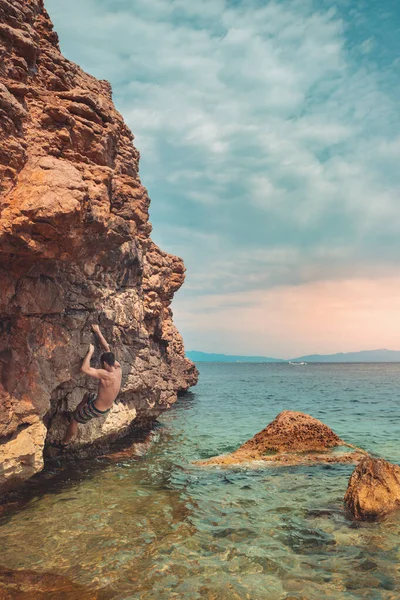 Ισχυρός Άνδρας Σκαρφαλώνει Βράχια Στην Παραλία Κατά Διάρκεια Της Πρωινής — Φωτογραφία Αρχείου