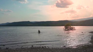 Nehirde kristal berrak suda yüzen çekici bir adam. Yaz havası ve tatil konsepti. Göle hoş geldiniz..